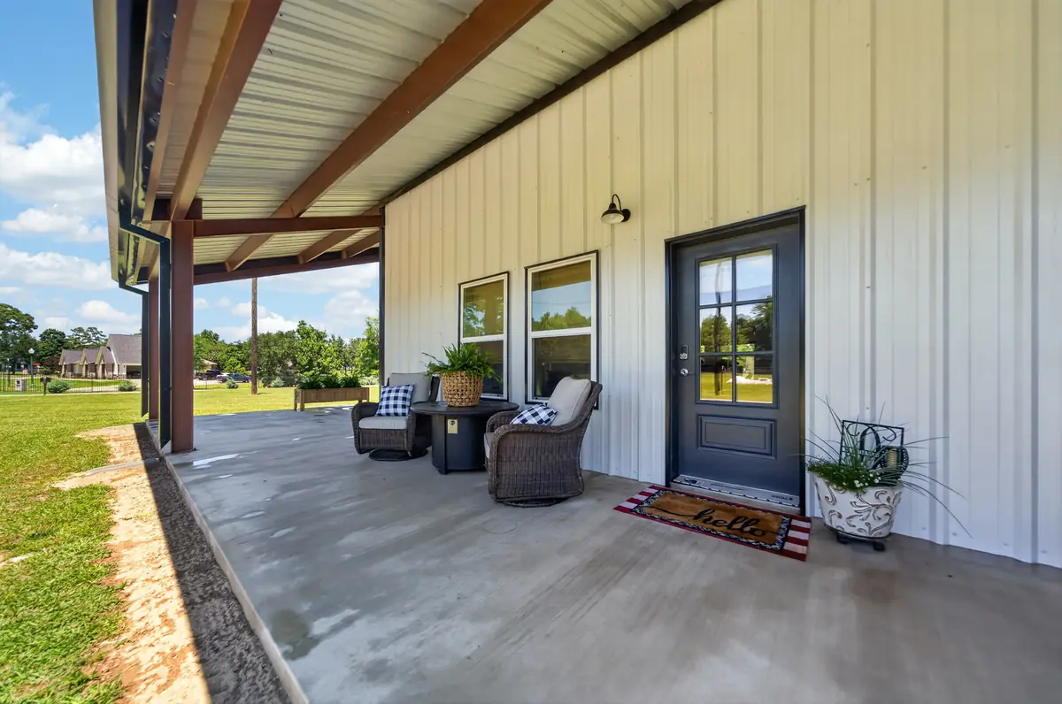 Covered wraparound porch with wicker seating and front entry, barndominium Chandler TX