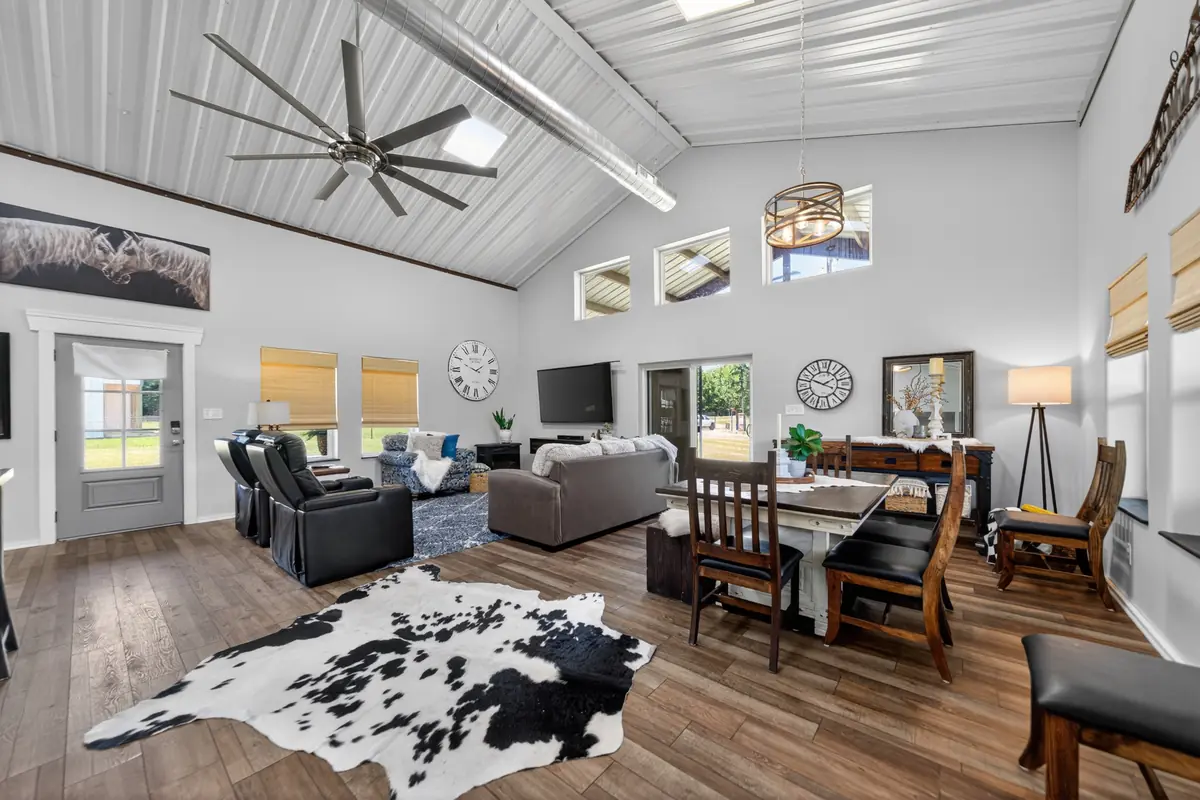 Open floor plan great room with soaring vaulted corrugated ceiling, large ceiling fan, living and dining areas, barndominium Chandler TX