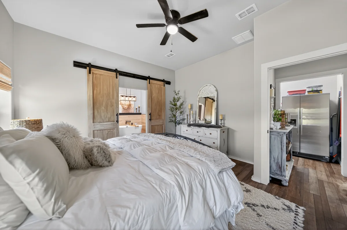 Primary bedroom with double sliding barn doors opening to spa bath, barndominium Chandler TX