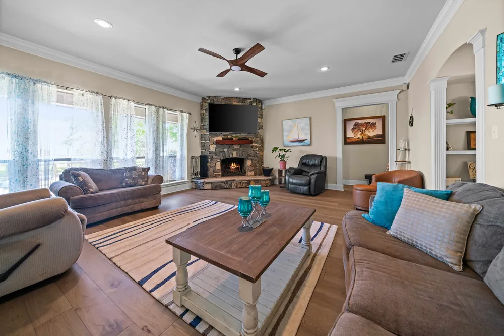 Spacious living room with stone wood burning fireplace hardwood floors and lake views at Sunrise Shores waterfront home Lake Palestine Chandler TX