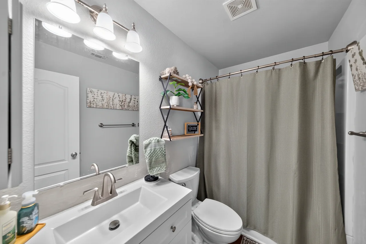 Hall bathroom with white vanity and tub with shower at 1054 Caroline Ln in Shadybrook, a gated Lake Palestine community in Bullard, TX.
