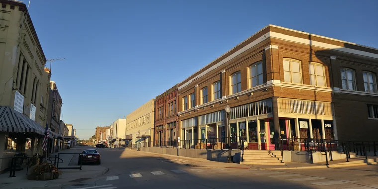Two-story brick storefronts along W. Oak Street in downtown Palestine, Texas, in early morning light.